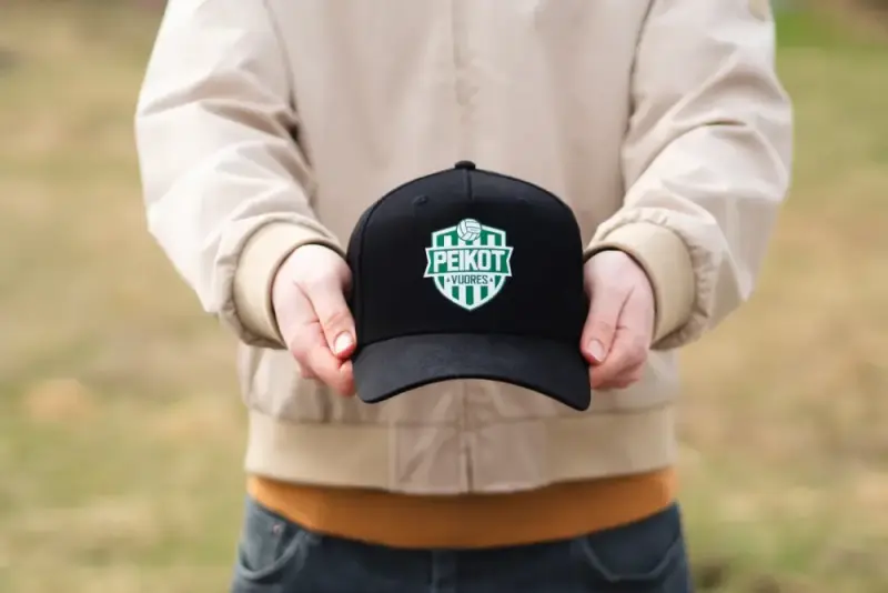 Peikot Vuores -lippis kädessä